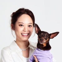 Photograph of laēlap founder Hanna Kang with a dog wearing a purple laēlap crewneck sweater
